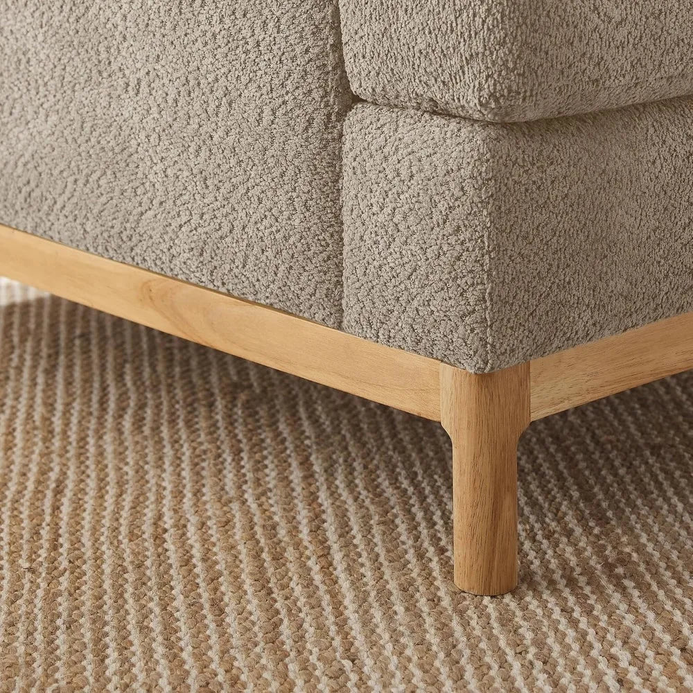 Close-up of the Oversized Mid Century Modern Armchair by Morsale with textured beige fabric. The wooden legs elegantly sit on a ribbed beige carpet, highlighting a cozy and neutral aesthetic true to Mid-Century Modern design.