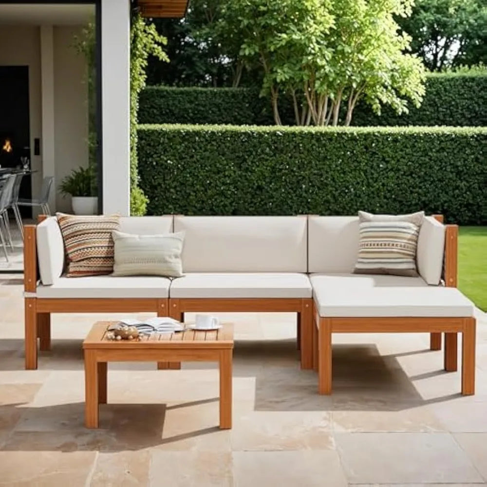 A modern outdoor patio features Morsale's Ryde Patio Sectional Sofa with beige cushions and patterned pillows, next to an Acacia wood table. Surrounded by lush greenery under a partially covered installation, it creates a serene oasis for relaxation.