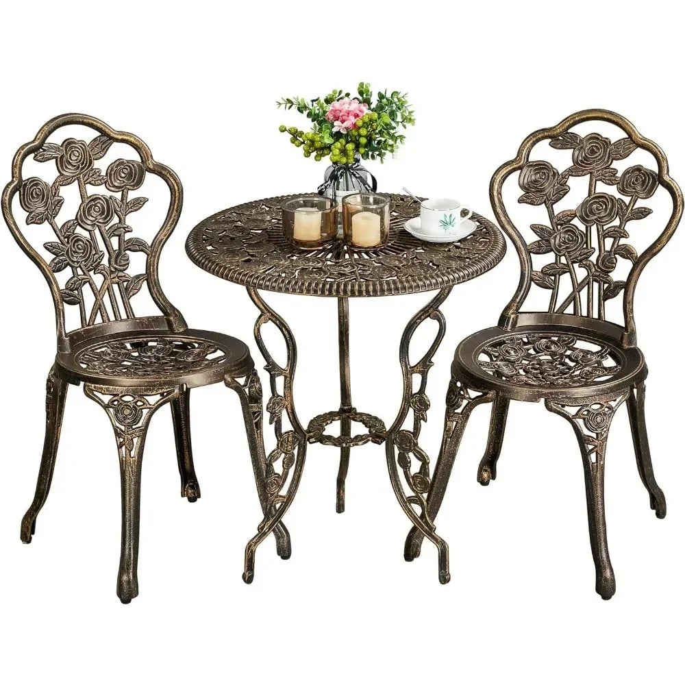 The Morsale Davids 3-Piece Vintage Outdoor Set includes two chairs and a round table with rose patterns, needing minimal assembly. The table elegantly holds two candles, a coffee cup, and a vase of pink and yellow flowers.