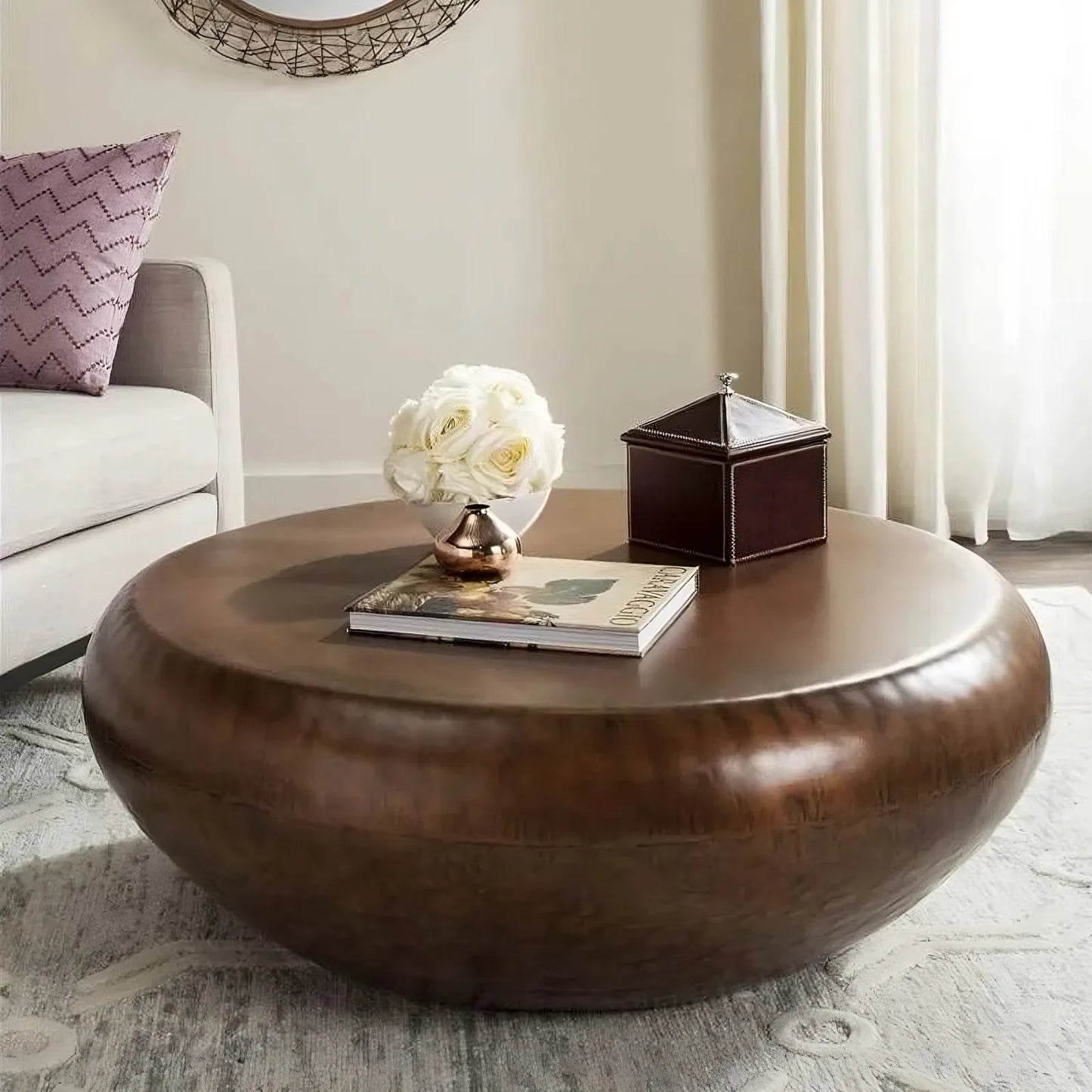 The 39" Iron Coffee Table by Morsale adds modern sophistication to the living room, adorned with a book, a decorative box, and a vase of white roses. It pairs elegantly with a light-colored sofa and patterned rug as sunlight streams through sheer curtains.
