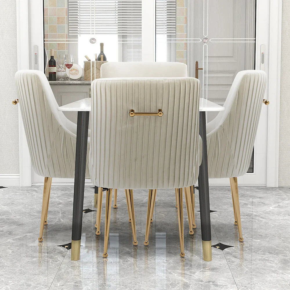 A modern dining room displays the Modern Glam Boucle Pleated Velvet Dining Chair Set of 4 by Morsale, featuring cream-colored seating with gold accents around a white table. It boasts marble flooring and soft-toned cabinets, epitomizing chic home furniture elegance.
