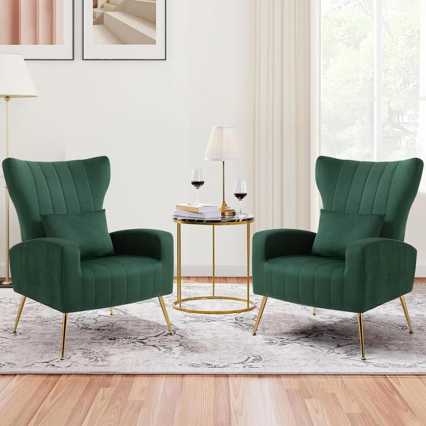 In a cozy living room, two Morsale Modern Velvet Lounge Chairs face each other with their gold metal legs. A round side table between them supports two glasses of red wine and a lamp, all set against light walls, wood flooring, large windows, and neutral décor.