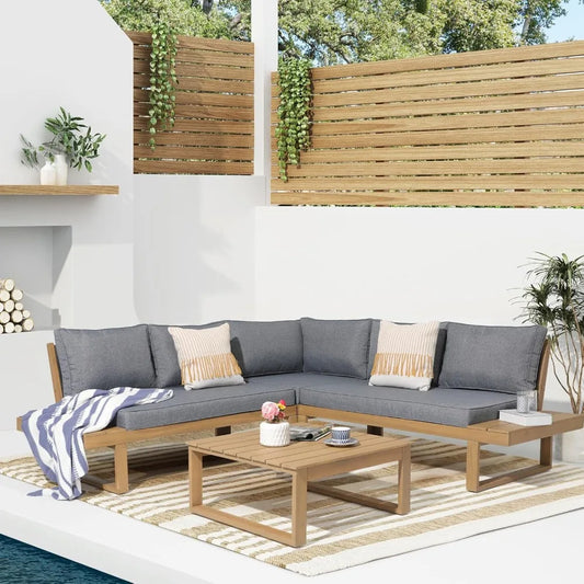 The patio features the modern Morsale Eaton Outdoor Sectional Sofa Set, complete with gray cushions and striped pillows. A sleek table displays a potted plant and cups. A striped rug covers the floor, while vertical wood slats and greenery adorn the backdrop. Nearby, logs are neatly stacked.