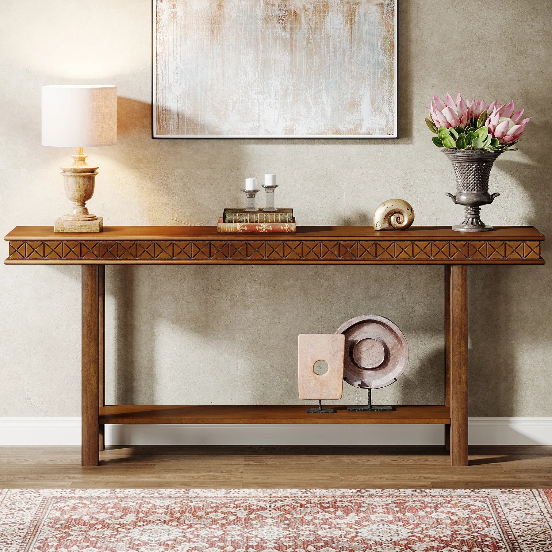 The Stanton Entryway Table With Storage by Morsale enhances the modern living room with a lamp, books, candles, a seashell, and a decorative vase of pink tulips against a textured wall. A framed artwork accents above while a patterned rug complements below.