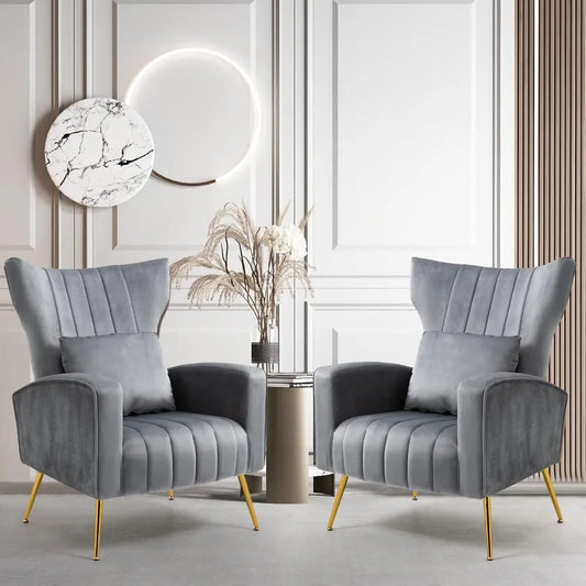 In a stylish room, the Modern Velvet Accent Chairs Set Of 2 by Morsale, featuring elegant gray upholstery and gold legs, are positioned around a small round table with a vase of dried flowers. A circular marble art piece and wooden paneling enhance the light-colored wall behind this chic display.