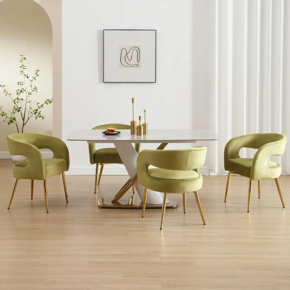 A modern dining room includes a white table on a wooden floor, flanked by Morsale's Velvet Dining Room Chairs in olive-green with gold legs. A minimalist abstract painting decorates the white wall, and a plant is visible near an archway.