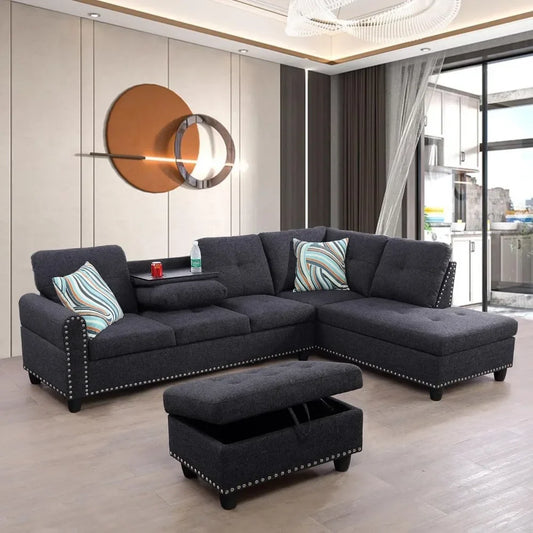 The modern living room showcases a Morsale Sectional Sofa With Ottoman in dark gray premium linen highlighted by studded accents. Adorned with decorative pillows featuring blue and brown swirls, it’s complemented by abstract wall art, offering an inviting view into the kitchen.