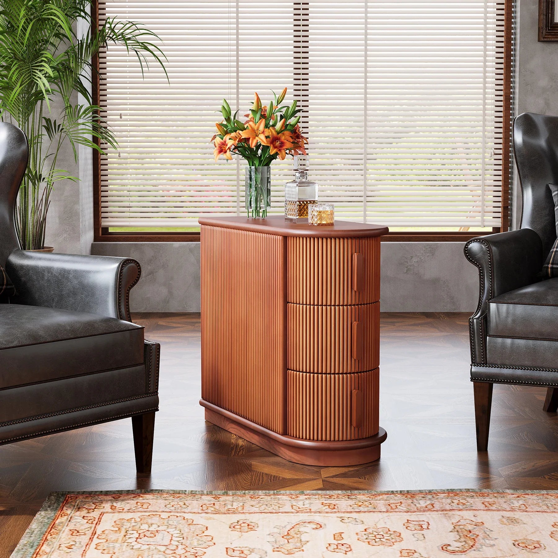 A stylish living room showcases two dark leather armchairs flanking the Morsale Irvine Solid Wood Side Table, featuring vertical grooves. A vase of orange lilies and decorative jars adorn the table. Natural light streams through large windows with horizontal blinds, highlighting a patterned rug.