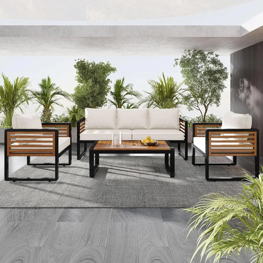 A vibrant outdoor patio scene showcases a Morsale 4-Piece Outdoor Patio Sectional Sofa Set, featuring white polyester cushions and wooden accents. It's centered around an acacia wood coffee table on a gray rug, surrounded by lush greenery beneath a bright sky.