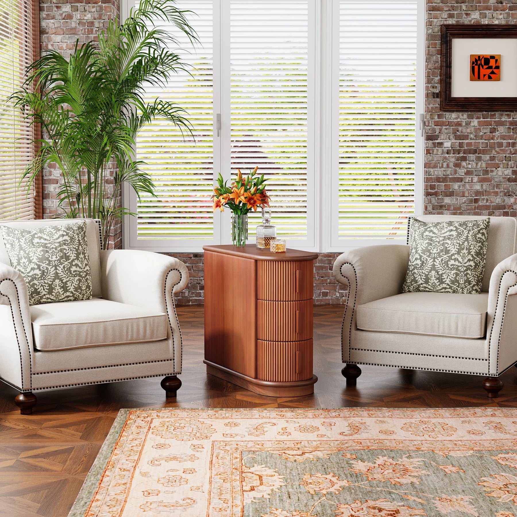 A cozy sitting area features two beige armchairs with decorative pillows around the Morsale Irvine Solid Wood Side Table. The space boasts a potted plant, large windows, and a brick wall for added charm, while a patterned rug and vintage finish complete this inviting setup.