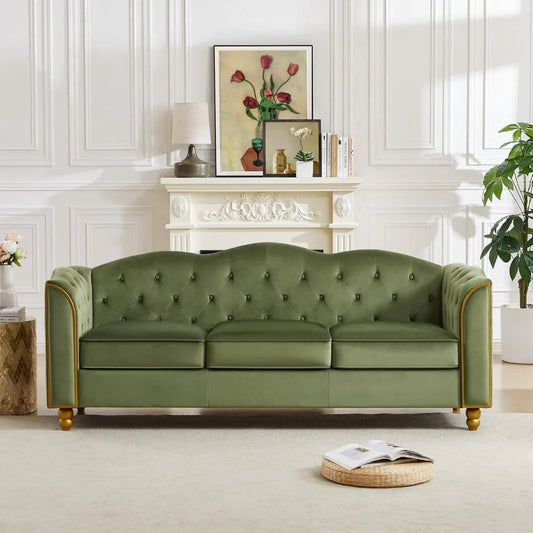 The Morsale 3-Seater Living Room Sofa Couch with a green tufted design and wooden legs stands out in this minimalist modern living room. A white fireplace displays a lamp and floral painting, while a small plant and woven basket on a light rug enhance the modern style.