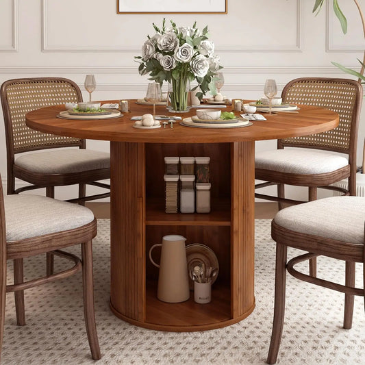 The Morsale Harrow 47" Round Dining Table with Storage exudes modern farmhouse design. A floral centerpiece adorns the table set with plates, glasses, and cutlery. Four cushioned chairs surround it, while a storage shelf underneath holds decorative items, completing the light and elegant room.