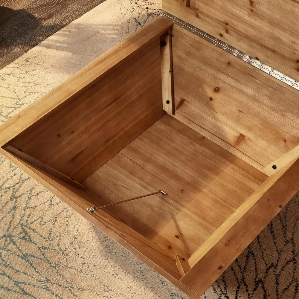 The Morsale Lift Top Farmhouse Coffee Table sits on a patterned rug, its wooden storage chest open to reveal a spacious interior and sturdy metal support hinge. It blends rustic charm with practical elegance.