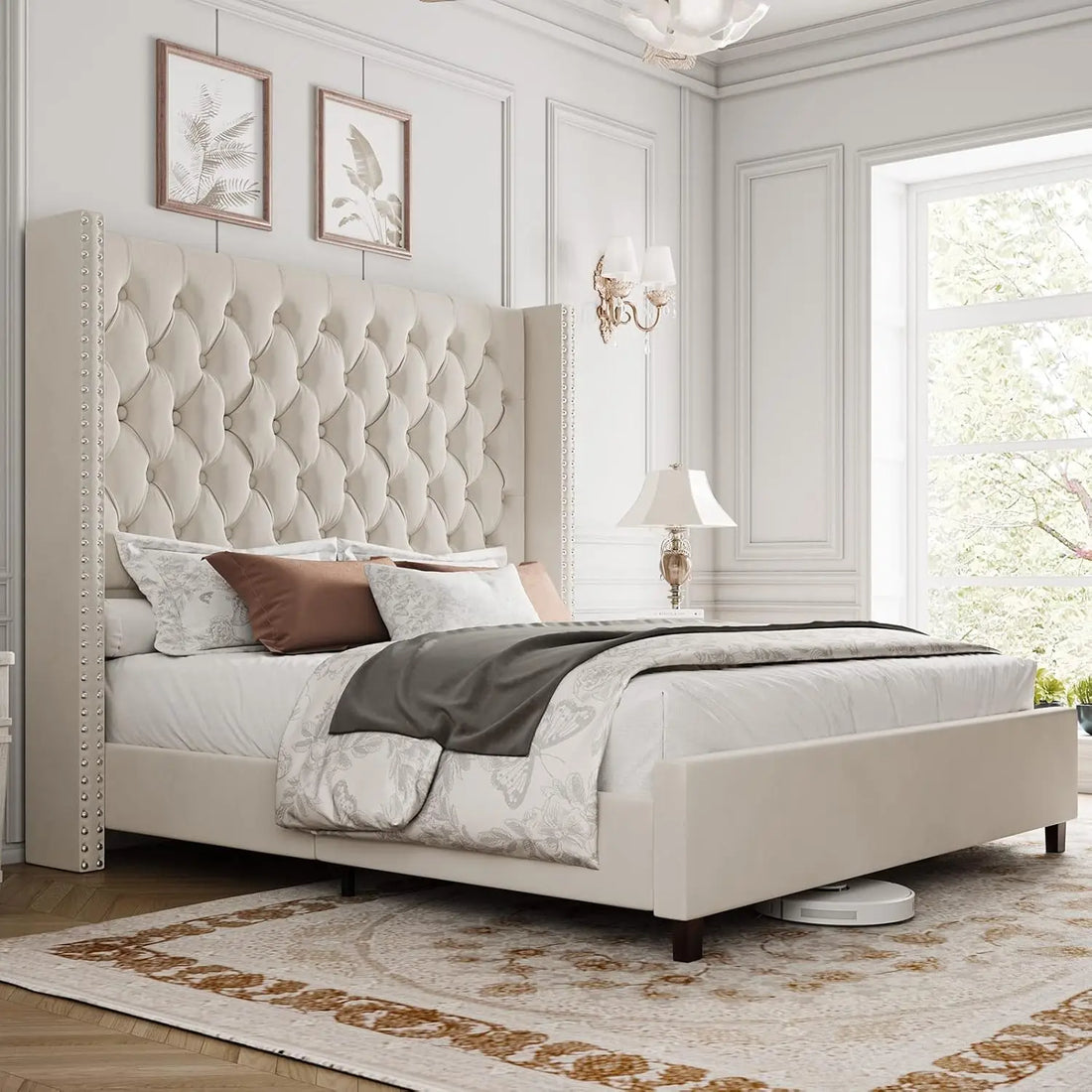A luxurious bedroom showcases Morsale's Velvet Tufted Bed with Headboard, complemented by beige and brown bedding. Elegant wall art hangs above, while a nightstand lamp enhances sophistication. A patterned rug decorates the wooden floor, and large windows invite natural light into the serene space.
