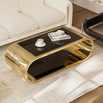 A modern living room features a Morsale Stainless Steel & Glass Coffee Table with a glossy black top, holding coffee and books. Its unique curved design beautifully contrasts with the white sofa and black chair on a textured rug.