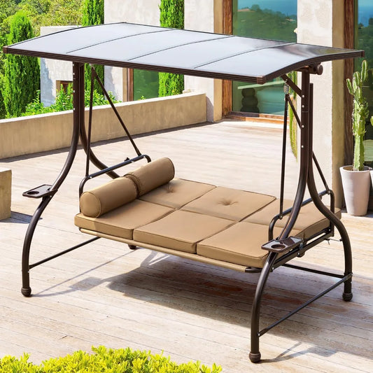 The Morsale Porch Swing With Hard Top, featuring a UV protection canopy, brown cushion, and cylindrical pillow, sits on a wooden deck. It blends beautifully with modern buildings and greenery.