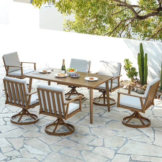 A modern patio scene showcases the Morsale Shefford 7-Piece Patio Dining Set with a wooden table and six cushioned chairs. The table is adorned with plates, a champagne bottle, glasses, and a fruit bowl. A large tree and cactus are in the background on the stone patio.