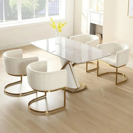 A modern dining room features minimalist decor with a white marble table paired with the Morsale Modena Dining Chair Set of 4, showcasing velvet white upholstery and gold metal frames. Light wood flooring, yellow flowers in a small vase, and large windows inviting natural light enhance the elegant vibe.