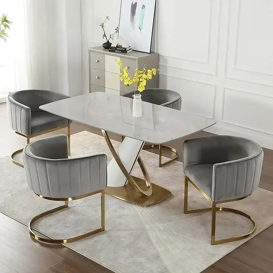 A modern dining room features a rectangular marble table with a gold twisted base, surrounded by four Morsale Modena Dining Chairs in gray linen. These chairs provide ergonomic support with cushioned seats and gold frames. A vase of yellow flowers sits on the table, complemented by abstract wall art.
