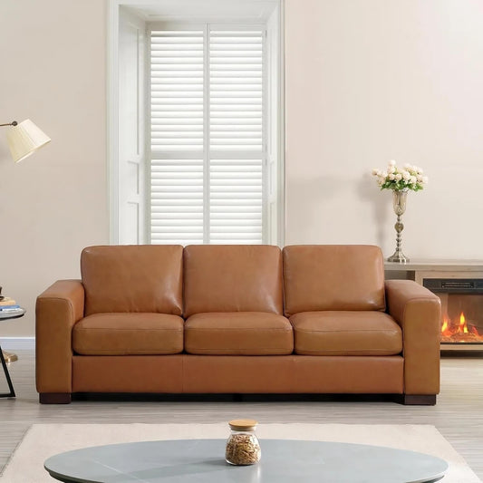 The living room features the Piazze Genuine Leather Sofa by Morsale in front of a large window with white shutters. To the left stands a modern floor lamp, while to the right, a fireplace emits a soft glow, and a round coffee table completes this modern-style setting.